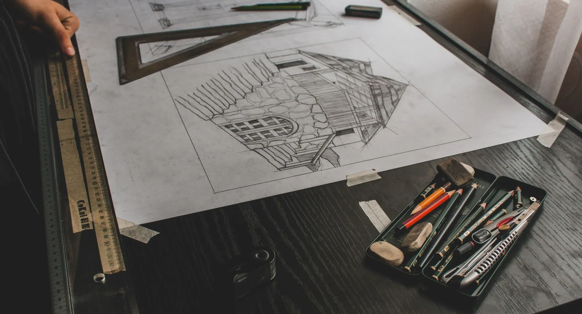 Sketsa bangunan di atas meja gambar bersama penggaris dan pensil